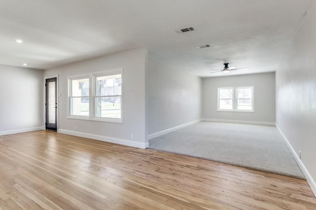 empty room with light wood-type flooring, baseboards, visible vents, and a ceiling fan