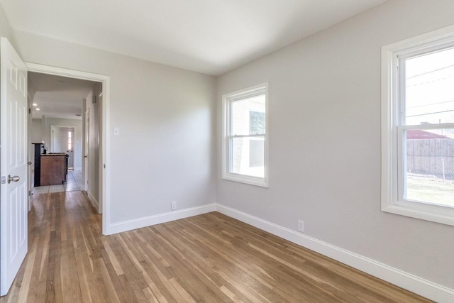unfurnished room with light wood-style flooring and baseboards