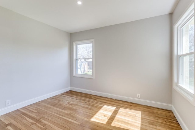 spare room featuring a wealth of natural light, light wood finished floors, and baseboards