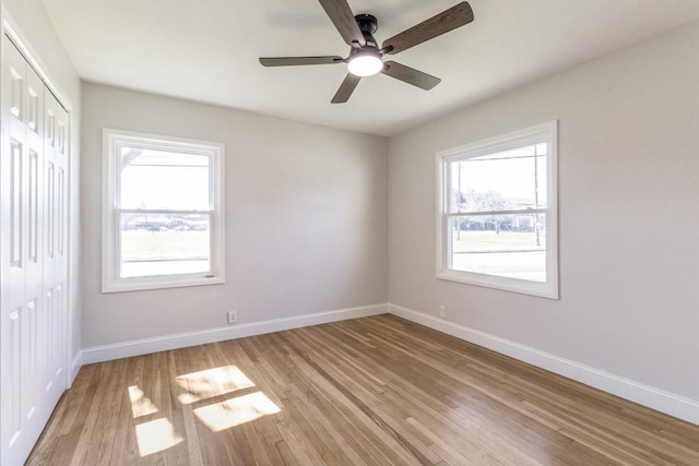 unfurnished bedroom featuring a closet, light wood-style flooring, multiple windows, and baseboards