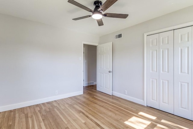 unfurnished bedroom featuring light wood-type flooring, a closet, baseboards, and visible vents