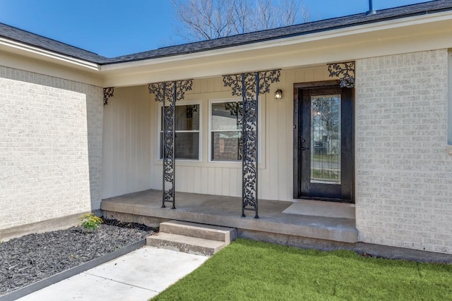 view of exterior entry with a porch and brick siding