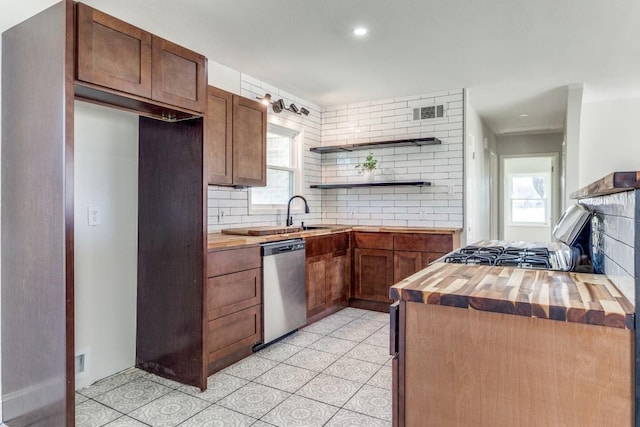 kitchen featuring open shelves, plenty of natural light, butcher block counters, stainless steel dishwasher, and decorative backsplash
