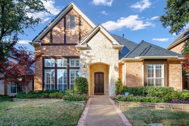 view of front of house featuring stone siding, a front yard, and brick siding