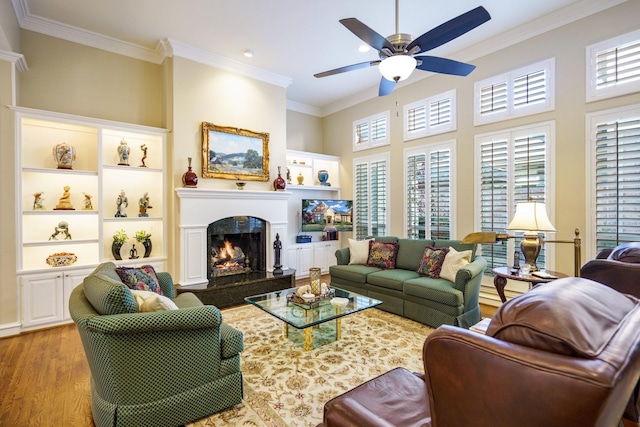 living room with a ceiling fan, crown molding, light wood-style flooring, and a premium fireplace