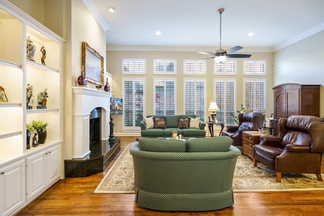 living room with ornamental molding, light wood-type flooring, and a high end fireplace