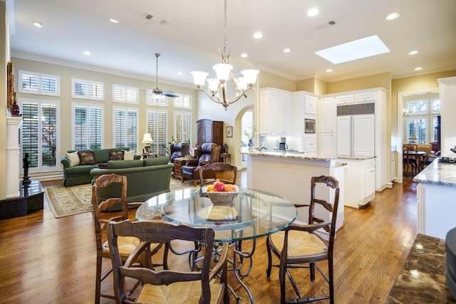 dining room featuring ornamental molding, a wealth of natural light, arched walkways, and wood finished floors