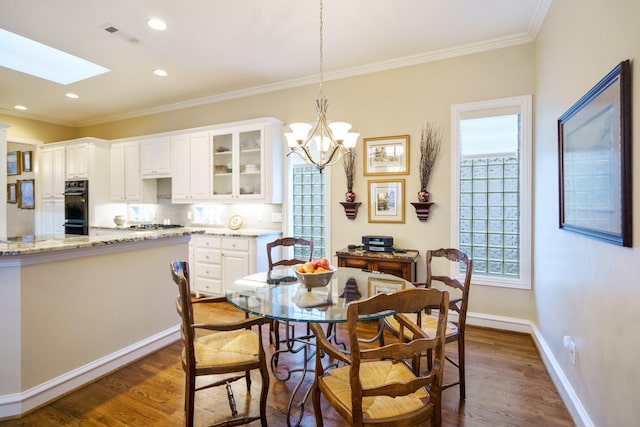 dining room featuring a skylight, baseboards, ornamental molding, dark wood-style flooring, and recessed lighting