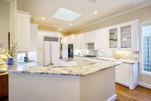 kitchen featuring a skylight, a kitchen island, light stone counters, and white cabinets