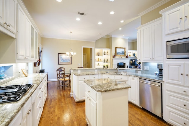 kitchen featuring a center island, pendant lighting, stainless steel appliances, white cabinetry, and a peninsula