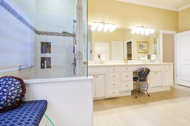 bathroom featuring double vanity, a stall shower, a sink, and crown molding