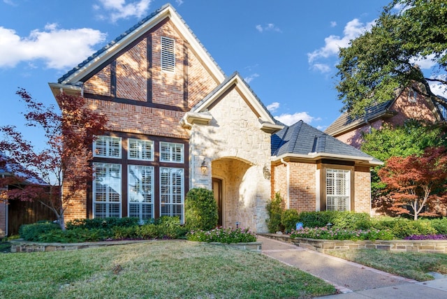 view of front of home featuring stone siding, brick siding, and a front yard