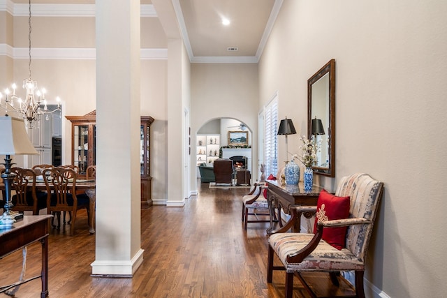 hall featuring dark wood-type flooring, a notable chandelier, ornamental molding, and baseboards