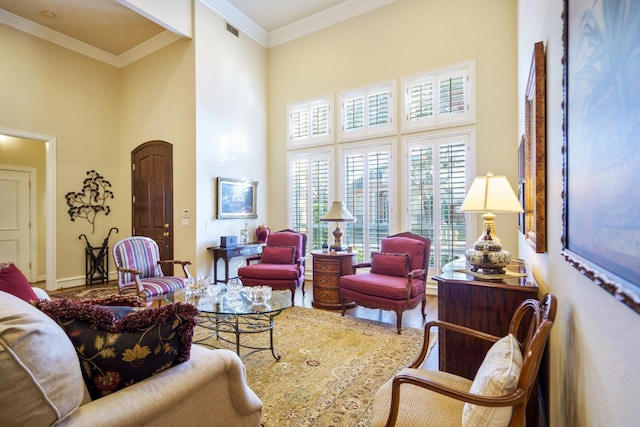 living room with baseboards, a high ceiling, visible vents, and ornamental molding