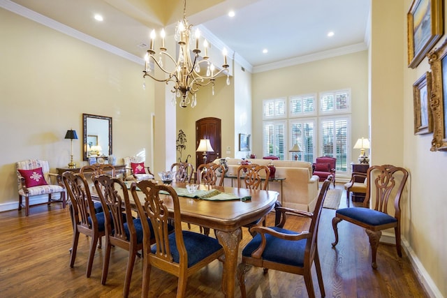 dining area with dark wood-style floors, ornamental molding, a towering ceiling, and baseboards