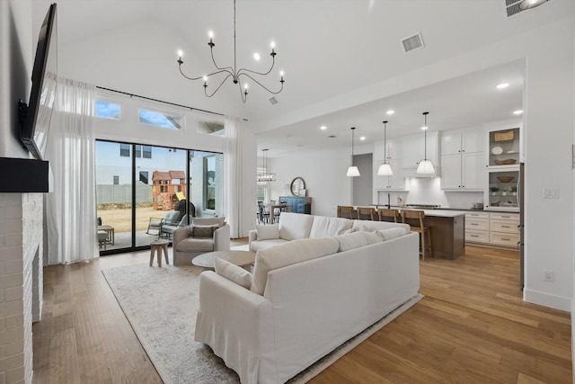 living room with a chandelier, recessed lighting, a fireplace, visible vents, and light wood finished floors