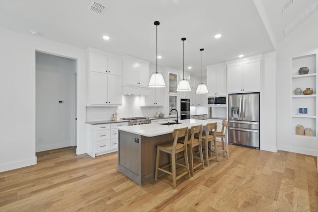 kitchen featuring a kitchen island with sink, appliances with stainless steel finishes, light wood-style flooring, and visible vents