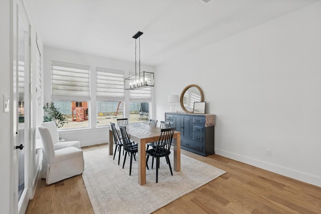 dining room with a chandelier, baseboards, and light wood finished floors