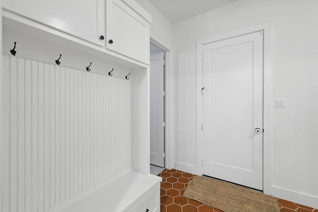 mudroom with dark tile patterned floors and baseboards