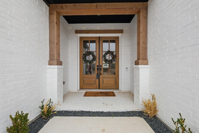 view of exterior entry with brick siding and french doors