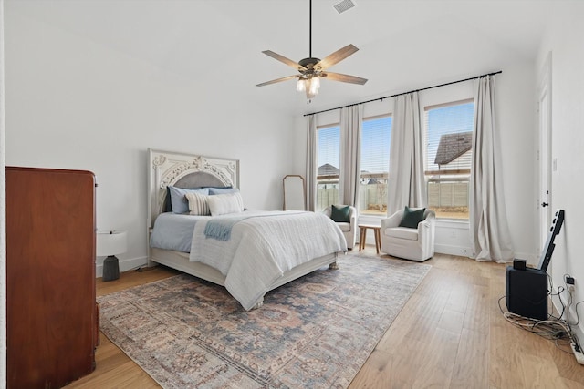 bedroom with ceiling fan, light wood finished floors, visible vents, and baseboards