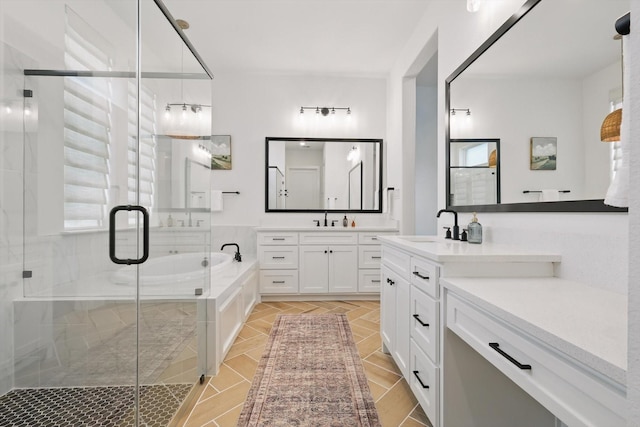 bathroom featuring a sink, two vanities, a shower stall, and a bath