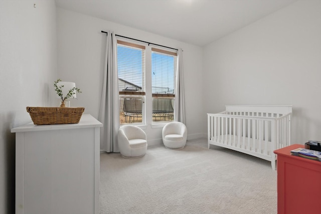 bedroom featuring carpet floors, a crib, and baseboards