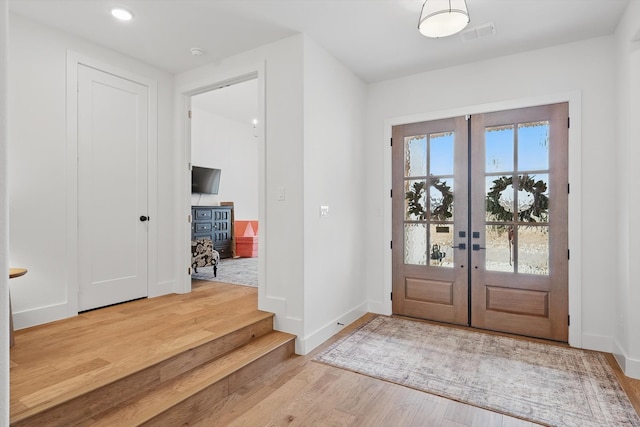 foyer with french doors, visible vents, baseboards, and wood finished floors