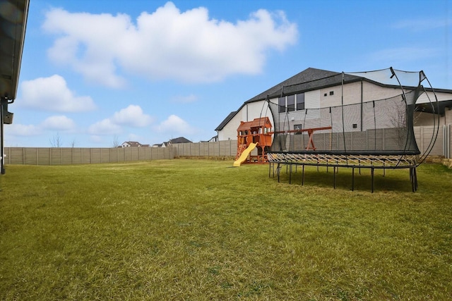 view of yard featuring a trampoline, a playground, and fence