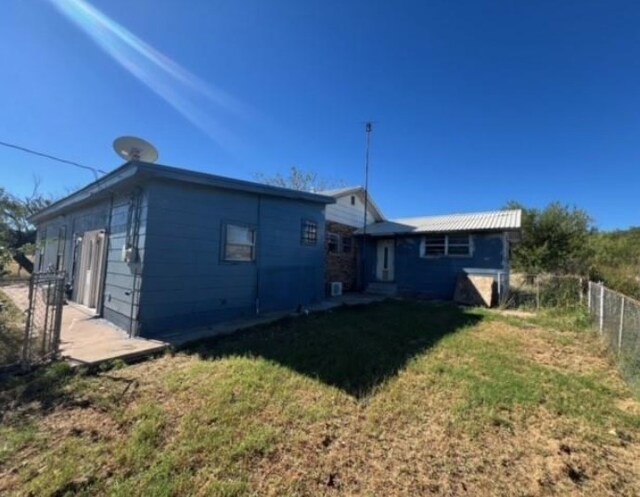 rear view of house featuring a lawn and fence