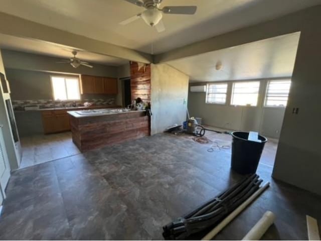 kitchen with a peninsula, brown cabinets, a ceiling fan, and open floor plan