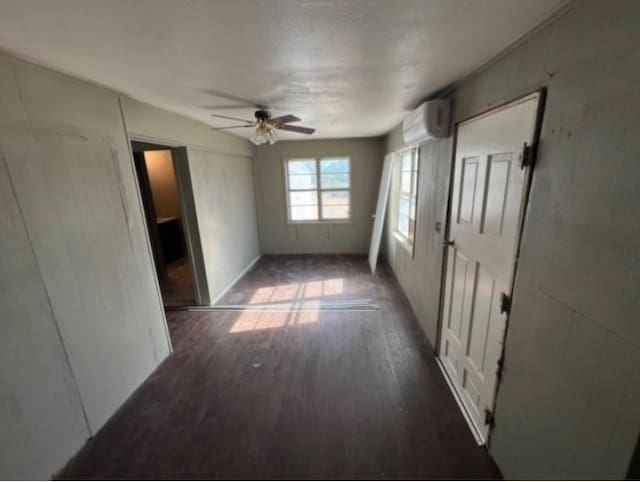 spare room with a ceiling fan, dark wood-type flooring, and a wall mounted AC