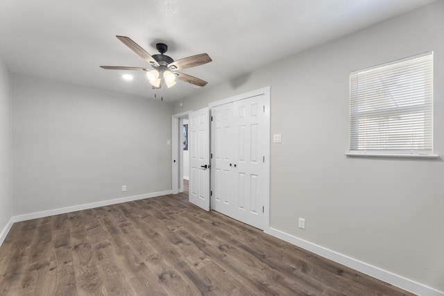 unfurnished bedroom with ceiling fan, a closet, wood finished floors, and baseboards