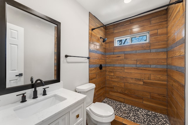 full bath with tiled shower, vanity, and toilet