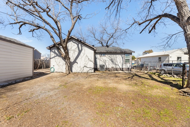 rear view of house with an outbuilding, central AC, and fence