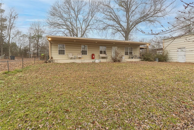 rear view of property featuring a patio area, fence, and a lawn