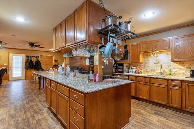 kitchen featuring light stone countertops, a kitchen island, brown cabinets, and a sink