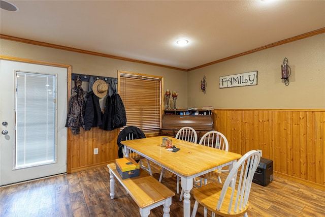 dining room with a wainscoted wall, wooden walls, and wood finished floors