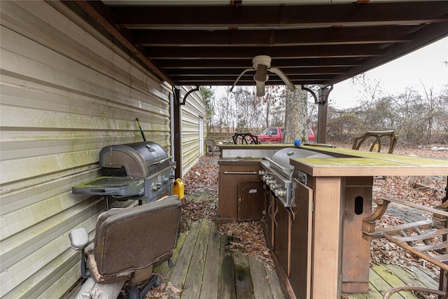 wooden terrace with ceiling fan, exterior kitchen, and area for grilling