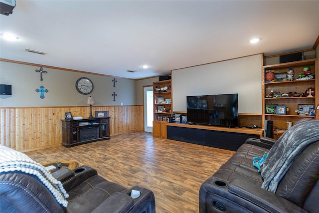 living area featuring wainscoting, wood finished floors, visible vents, and crown molding