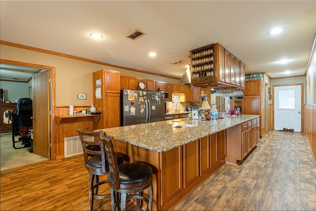 kitchen with visible vents, a peninsula, brown cabinetry, and freestanding refrigerator