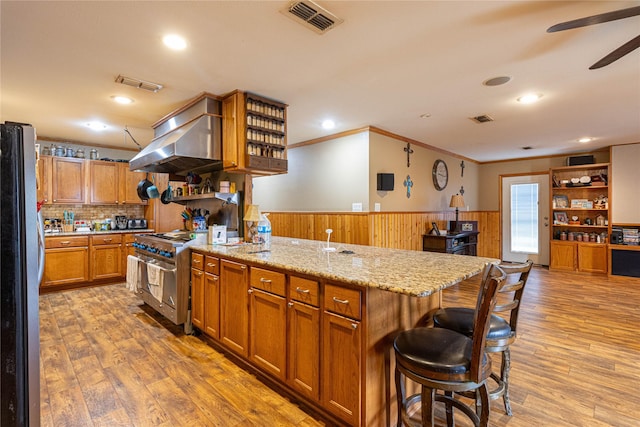 kitchen featuring exhaust hood, visible vents, appliances with stainless steel finishes, wainscoting, and open shelves