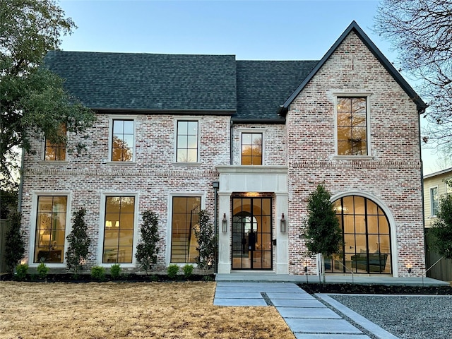 view of front of home with brick siding, a front lawn, and roof with shingles