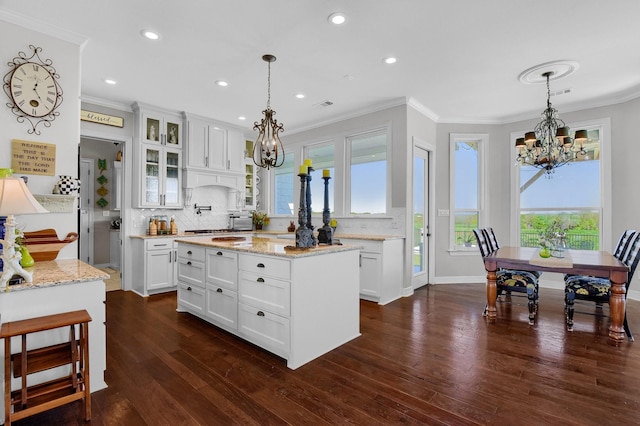 kitchen with glass insert cabinets, white cabinetry, a kitchen island, and hanging light fixtures