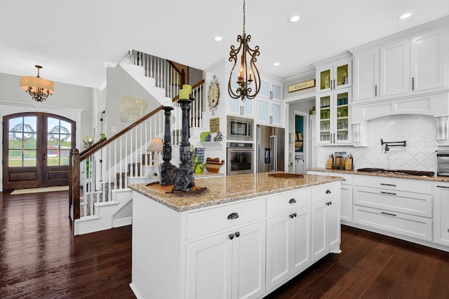 kitchen with french doors, appliances with stainless steel finishes, a kitchen island, and white cabinetry