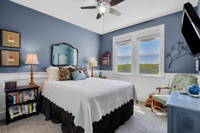 bedroom featuring a ceiling fan, carpet, and wainscoting