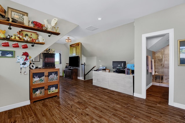 interior space with dark wood-style floors, lofted ceiling, visible vents, and baseboards