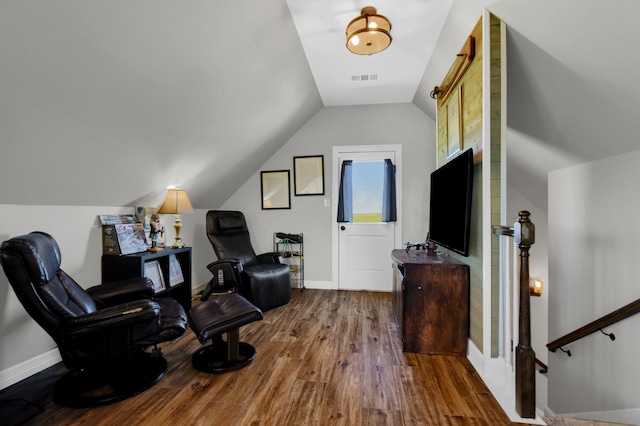 sitting room featuring visible vents, vaulted ceiling, baseboards, and wood finished floors