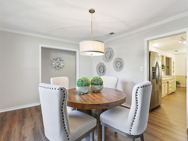 dining space featuring dark wood-style floors, visible vents, ornamental molding, and baseboards