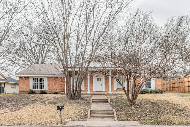 view of front of home featuring brick siding, fence, and central air condition unit